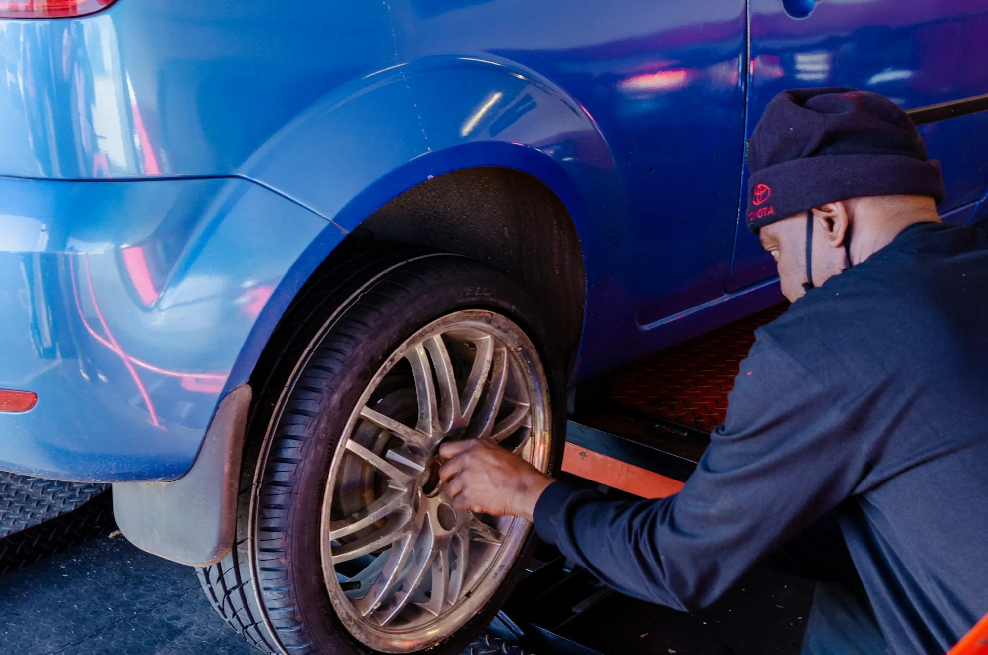 Mechanic tightening the wheel of a blue car